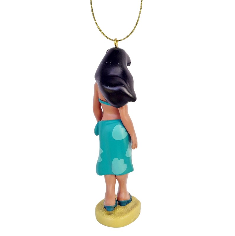 Peut inclure: Un collier pendentif avec une figurine de femme aux cheveux noirs, portant un haut de bikini bleu et une jupe turquoise avec des formes de fleurs blanches. La figurine est sur une base jaune, et le collier a une cha&icirc;ne dor&eacute;e.