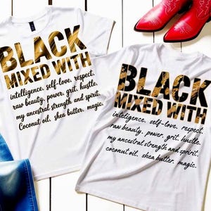 Peut inclure: Deux t-shirts blancs avec le texte "BLACK MIXED WITH" en lettres noires et dorées. En dessous du texte, des mots supplémentaires en écriture script. Des bottes de cowboy rouges sont visibles en arrière-plan.