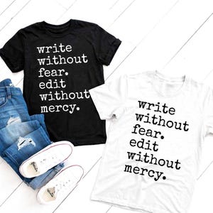 May include: Two t-shirts, one black and one white, with the text "write without fear. edit without mercy." in a bold, typewriter font. The shirts are displayed with blue jeans and white trainers.
