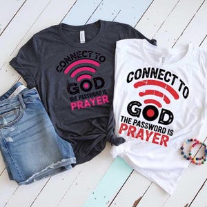 May include: Two t-shirts with a graphic design of a wifi symbol with the word "God" inside the symbol. The text "Connect to God" is above the symbol and the text "The password is prayer" is below the symbol. One shirt is dark grey and the other is white.