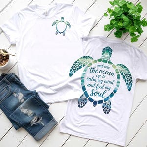 Peut inclure: Deux t-shirts blancs avec un motif de tortue de mer. L'un a une petite tortue sur le devant, l'autre une plus grande avec le texte "and into the ocean I go to calm my mind and feed my soul". Un short en jean bleu est également dans l'image.