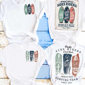 Peut inclure: T-shirts blancs avec des motifs de planches de surf. Un motif présente trois planches de surf avec le texte : "1984 Surfing The Waves Ole Scol Board." Un autre motif dit "Pacific Sides Riders" avec des planches de surf.