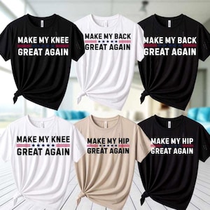 May include: Assorted t-shirts with the phrases "MAKE MY KNEE GREAT AGAIN", "MAKE MY BACK GREAT AGAIN", and "MAKE MY HIP GREAT AGAIN" in white text with red and blue accents. The shirts are black, white, and tan.