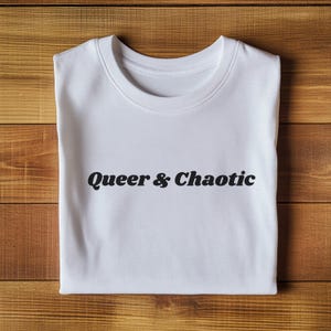 May include: White t-shirt with the text "Queer & Chaotic" printed in black.