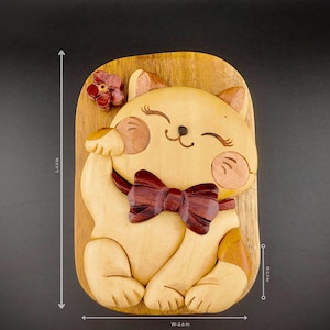 Puede incluir: Caja de rompecabezas de madera con forma de gato con una pajarita roja. El gato está sentado con la pata levantada. La caja mide 2,6 pulgadas de ancho y 4,4 pulgadas de alto.