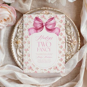 May include: Pink and white floral invitation with a large pink bow. The text reads "Hailey's Two Fancy" and includes details for a second birthday celebration.
