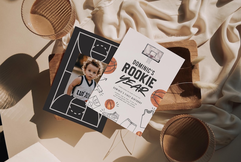 May include: A basketball-themed birthday invitation with a photo of a child in a basketball jersey. The invitation says "Dominic's Rookie Year" and features a basketball hoop, basketballs, and a basketball jersey.