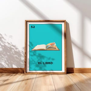 May include: Framed art print featuring a teal background with an open book illustration. The number "52" is in the top left corner, and the text "EL LIBRO" is at the bottom. The frame is a light brown color.
