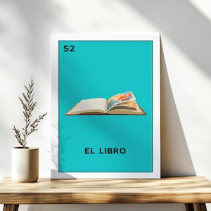 May include: A framed print featuring a teal background with the number 52 in the top left corner. The image depicts an open book with colorful illustrations. The text "EL LIBRO" is printed at the bottom of the image.
