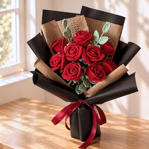 May include: A bouquet of crocheted red roses with light green crocheted leaves. The flowers are wrapped in layers of black and brown honeycomb paper, secured at the base with a dark red satin ribbon tied in a bow at the center of the stems.