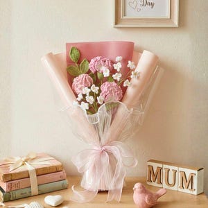 May include: A bouquet of pink crocheted flowers with green leaves and white accents, wrapped in pink paper and tied with a sheer pink ribbon. The words "Premium Pink" are at the top left. A framed sign says "Happy Mother's Day".