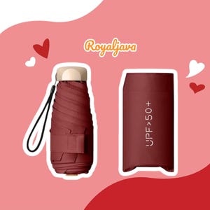 Puede incluir: Un paraguas compacto burdeos con mango de madera y correa negra. El paraguas está cerrado y tiene una etiqueta que dice "UPF>50+".