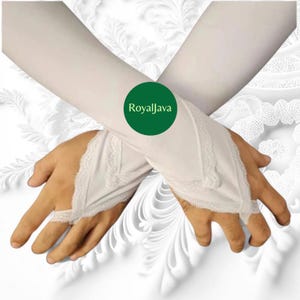 May include: White fingerless gloves with lace trim. The gloves extend up the arm and feature a delicate lace detail around the wrist and hand opening. The gloves have the text "RoyalJava" on a green circle.