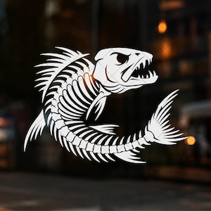 Op de afbeelding: Een witte vinyl sticker met een gestileerde grafische illustratie van een vissenskelet. Het ontwerp toont de skeletresten van een vis met een agressieve uitdrukking, een open mond, scherpe tanden en gedetailleerde ribben en vinnen.