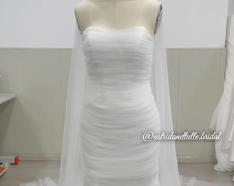 May include: A strapless white wedding dress on a mannequin. The dress features a ruched bodice and a flowing skirt. A sheer, draped veil is attached to the mannequin. The text "@astridandtulle.bridal" is visible.