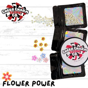 Puede incluir: Una bolsa negra resellable llena de abalorios blancos con forma de flor. La bolsa está etiquetada con "Cheer Charm Slime Co. Made by Riley T." La imagen también muestra una variedad de abalorios con forma de flor de colores esparcidos sobre una superficie de madera blanca. El texto "Flower Power" está escrito debajo de la imagen.