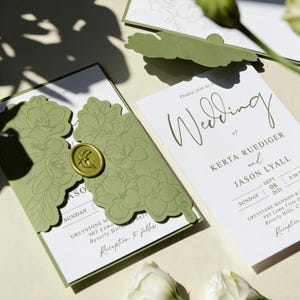 Puede incluir: Conjunto de invitaciones de boda con un diseño floral verde. La invitación incluye los nombres Kerta Ruediger y Jason Lyall, con la fecha 8 de septiembre de 2025. Un sello de cera dorado y recortes florales añaden elegancia.