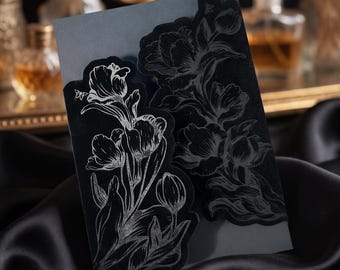 May include: Black floral design stickers with a silver outline. The stickers feature detailed illustrations of tulips and leaves. The stickers are on a dark gray background, with a black satin fabric in the background.