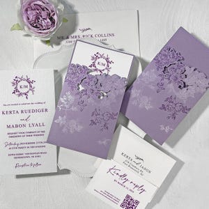 Puede incluir: Un conjunto de invitaciones de boda y tarjetas de respuesta de color lavanda. Las invitaciones presentan recortes florales e incluyen los nombres Kerta y Mabon, y la fecha de la boda. Las tarjetas de respuesta incluyen los nombres Kerta y Jason y un código QR.
