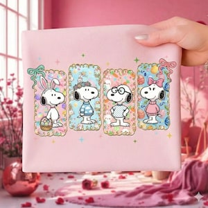 Puede incluir: Una funda de almohada rosa claro con cuatro diseños de Snoopy con temática de Pascua. Cada Snoopy está enmarcado con un borde decorativo y un lazo. Un Snoopy lleva orejas de conejo y sostiene una cesta. Los otros Snoopy llevan gafas, una corona floral y un lazo rosa.