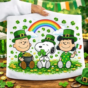 Puede incluir: Cojín blanco con un diseño del Día de San Patricio con personajes de dibujos animados, un arcoíris y tréboles. Los personajes llevan sombreros verdes y sostienen una olla de oro y un trébol.