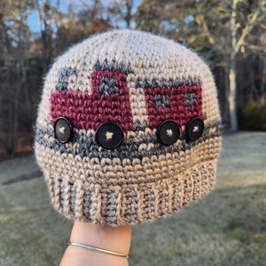 May include: A crocheted beanie hat with a red, white, and gray striped pattern. The hat has four black buttons on the front.