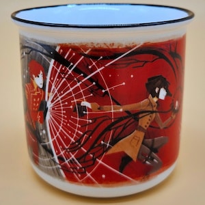 May include: White enamel mug with a red background featuring anime-style illustrations. The design includes two figures, a web-like structure, and dark, flowing lines. The rim is white with a blue interior.