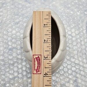 Peut inclure: Un vase blanc en c&eacute;ramique en forme d'&oelig;uf avec une surface textur&eacute;e. Une r&egrave;gle en bois est plac&eacute;e &agrave; l'int&eacute;rieur du vase, mesurant environ 10 cm de hauteur. Le vase a un int&eacute;rieur sombre et est pos&eacute; sur un fond en papier bulle.