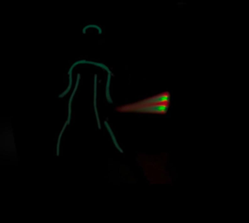 Pu&ograve; includere: Un omino verde con un raggio di luce rosso e verde che esce dal suo lato.