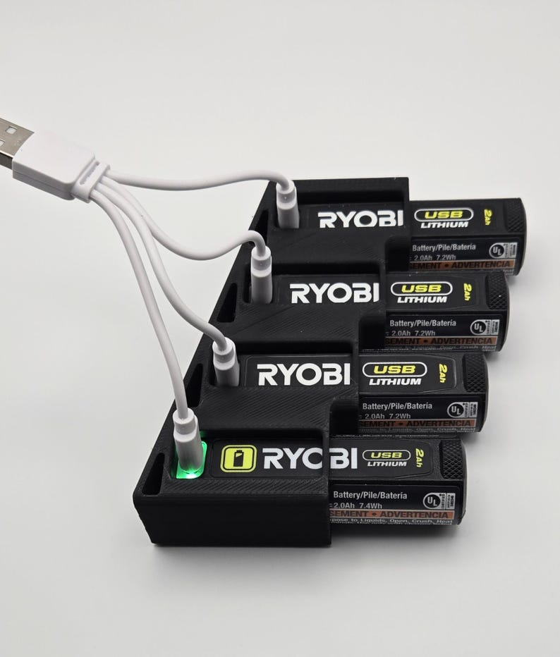 May include: A black Ryobi battery charging station with four USB lithium batteries. The batteries are labelled with "USB Lithium" and "2.0Ah 7.2Wh". A white USB cable is connected to the charging station.