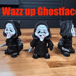 Puede incluir: Tres figuras de Ghostface con m&aacute;scaras blancas, t&uacute;nicas negras con capucha y cuchillos plateados, cada una con la lengua fuera. El texto Wazz up Ghostface aparece en letras rojas sobre las figuras.