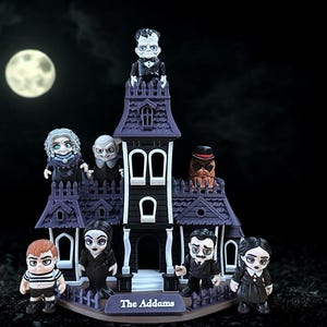 May include: A miniature haunted house with figurines of the Addams Family. The house is purple with white trim, and the characters are dressed in their iconic outfits. A full moon is in the background.
