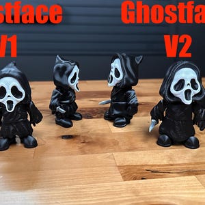 Puede incluir: Seis peque&ntilde;as figuras de Ghostface en blanco y negro mostradas en dos grupos etiquetados como Ghostface V1 y Ghostface V2. Cada figura viste una t&uacute;nica negra con capucha y una m&aacute;scara blanca con expresi&oacute;n de grito, algunas sostienen un peque&ntilde;o cuchillo plateado.