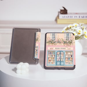 Op de afbeelding: Een zwarte tablet hoes met een kleurrijke illustratie van een boekhandelfa&ccedil;ade met de tekst "BOOK STORE". Het ontwerp omvat een blauwe deur, boekenplanken en bloemaccenten. Een doorzichtige tablethoes is ook zichtbaar.