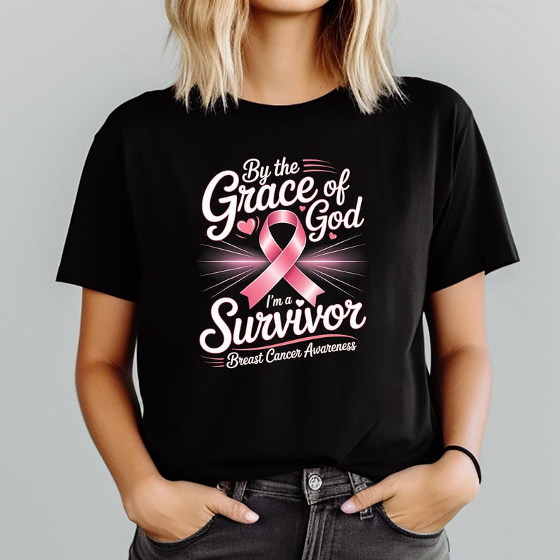 May include: Black t-shirt featuring a pink ribbon and the words "By the Grace of God I'm a Survivor" in white. The shirt also includes the text "Breast Cancer Awareness".