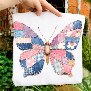 Pode incluir: Saco tote branco com um grande desenho de borboleta. A borboleta &eacute; feita de tecido patchwork em tons de rosa, azul e roxo. As asas t&ecirc;m padr&otilde;es florais, xadrez e lisos. O corpo da borboleta &eacute; marrom claro.