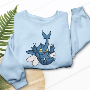 May include: A light blue sweatshirt featuring an embroidered cartoon beetle design. The beetle is blue with white wings and yellow eyes. The sweatshirt has a crew neck and long sleeves.