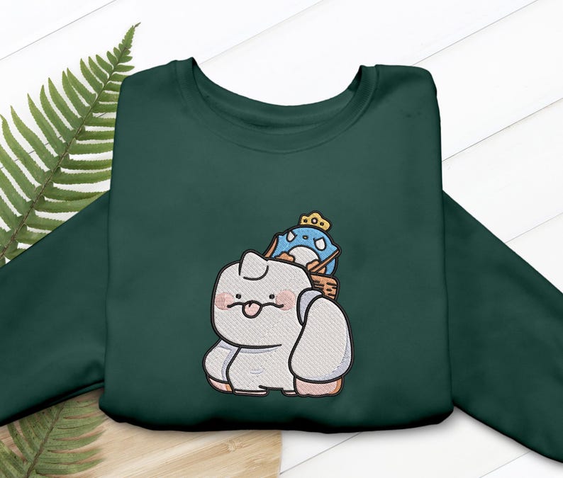 May include: Dark green sweatshirt featuring an embroidered design of a cartoon character carrying a blue penguin wearing a crown. The design is in shades of white, gray, pink, and blue. The sweatshirt is made of a soft material.