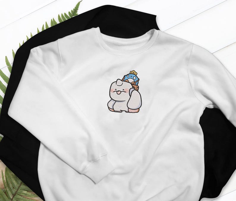May include: A white sweatshirt with a black sweatshirt underneath. The white sweatshirt features an embroidered cartoon design of a light gray creature carrying a blue and yellow character on its back. The design is centered on the chest.