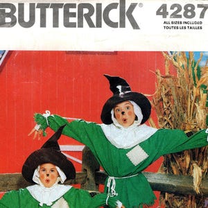Pode incluir: Padrão de costura Butterick 4287 para fantasias de espantalho infantis. As fantasias apresentam tops verdes com golas e remendos brancos, combinados com calças laranja. Os acessórios incluem chapéus pretos, baldes de abóbora e sapatos marrons. O fundo inclui um celeiro vermelho e abóboras.