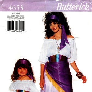 May include: Butterick 4653 sewing pattern envelope featuring a costume with a white off-the-shoulder blouse, a purple skirt with a gold fringe trim, a multicolored metallic sash, and a matching headscarf, shown on both an adult and a child.