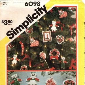 Könnte beinhalten: Ein Vintage-Nähmuster von Simplicity zum Nähen von Weihnachtsornamenten. Das Muster enthält Anleitungen zum Nähen einer Vielzahl von Ornamenten, darunter eine Katze, ein Strumpf, ein Schaukelpferd, ein Kranz, eine Kerze und ein Zuckerrohr. Das Muster ist mit der Nummer 6098 versehen und kostet 3,50 $.