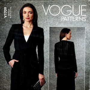 May include: Vogue Patterns sewing pattern for a black long-sleeved wrap coat with a V-neckline and a belt. The pattern is designed by Guy Laroche.