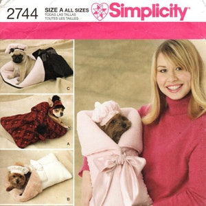 May include: A sewing pattern for making dog beds and carriers. The pattern includes four different designs: a red and black bed, a white and pink bed, a pink carrier, and a pink and blue bed. The pattern is from Simplicity and is size A for all sizes.