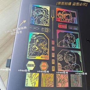 May include: A collection of holographic stickers featuring anime characters and text. The stickers have a metallic sheen and include the names "ASUKA", "MARI", "REI", and "KAWORU". Additional text includes "EMERGENCY" and "Eva".