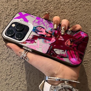 May include: A smartphone case with a colourful graphic design. The case displays a character illustration in pink, red, and blue, with the text "SO COOL" in white. The case has a black border and a silver camera frame.