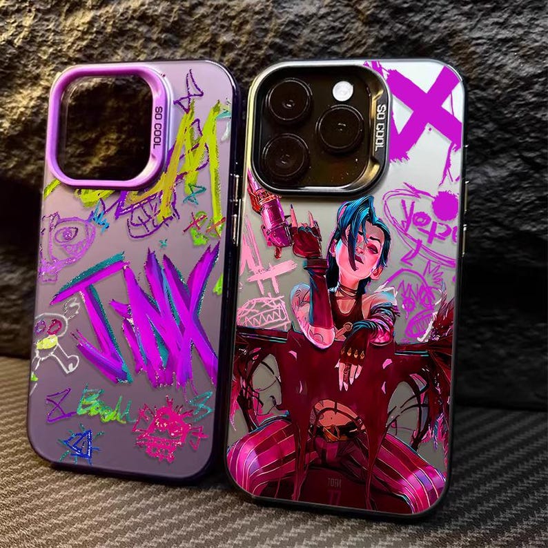 May include: Two phone cases with colorful designs. One case is purple with the word "JINX" in large pink letters and graffiti-style art. The other case features a character with blue hair holding a weapon, with pink and purple accents.
