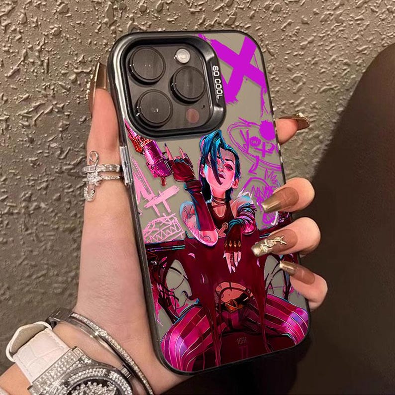 May include: A black and clear phone case featuring a colorful illustration of a character with blue hair and a weapon. The case has a silver border and the text "SO COOL" is visible. The design includes pink, purple, and red accents.