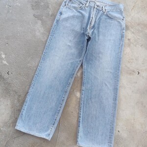 May include: Light blue denim jeans with a classic five-pocket design. The jeans have a straight leg cut and a button and zipper closure. The fabric appears to be a medium weight denim.