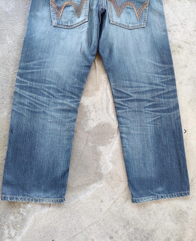 Peut inclure: Jean en denim bleu clair avec des coutures d&eacute;taill&eacute;es sur les poches arri&egrave;re. Le jean pr&eacute;sente un d&eacute;lavage et des d&eacute;tails subtils. Le style g&eacute;n&eacute;ral est d&eacute;contract&eacute; et classique, adapt&eacute; au quotidien.
